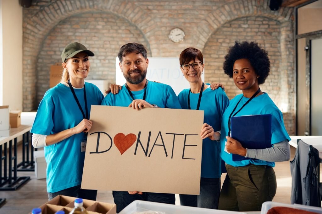 Our Work 8 Diverse volunteers inviting people to donate to charity and looking at camera.